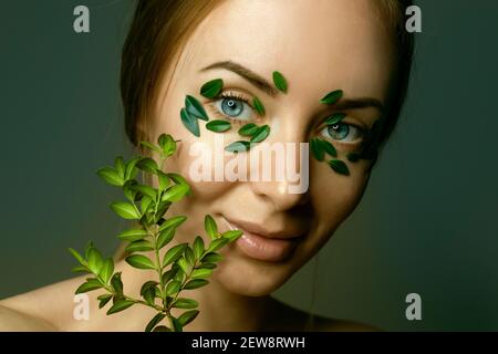 Nahaufnahme`s Gesicht einer jungen Frau mit Buchsbaumblättern. Spa und Wellness Konzept Vorlage Banner für Design. Werbung für kosmetische Produkte Stockfoto